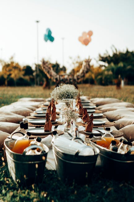 A long outdoor table set for a picnic or event at Hornchurch Country Park, featuring a floral arrangement in a glass vase with delicate white baby's breath, surrounded by folded brown napkins and glas