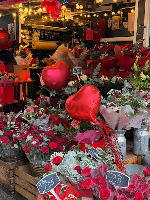 A vibrant display of floral arrangements and bouquets inside a flower shop, featuring a variety of fresh red roses, white flowers, and green foliage, all wrapped in decorative paper and ribbon. Promin